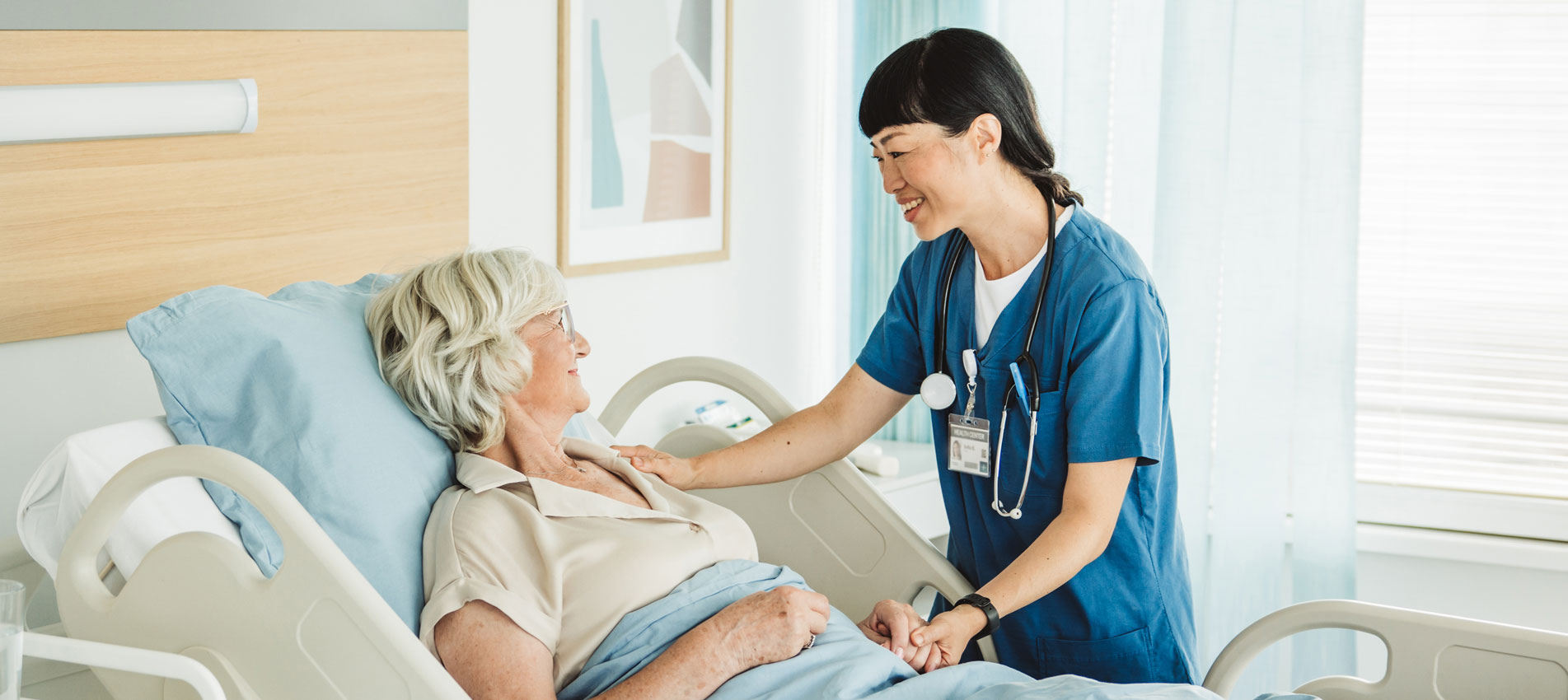 Nurse Talking To Senior Woman In Hospital Bed