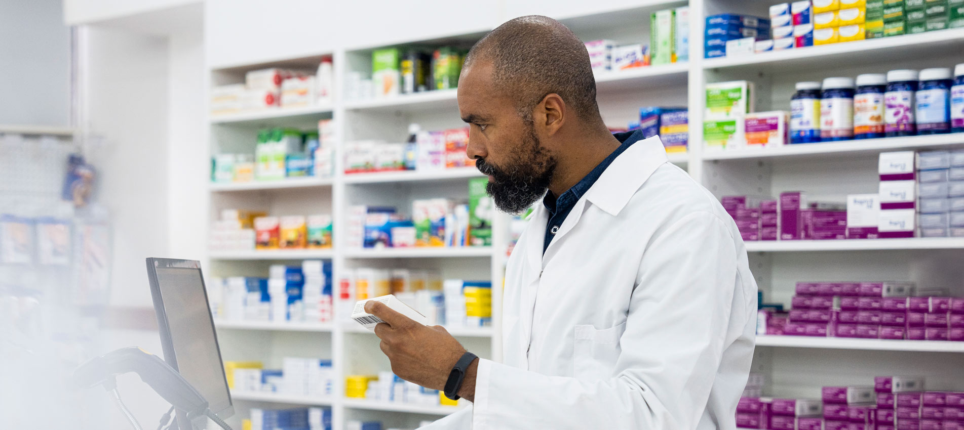 African American Pharmacist Typing Report On Computer Inside Pharmacy