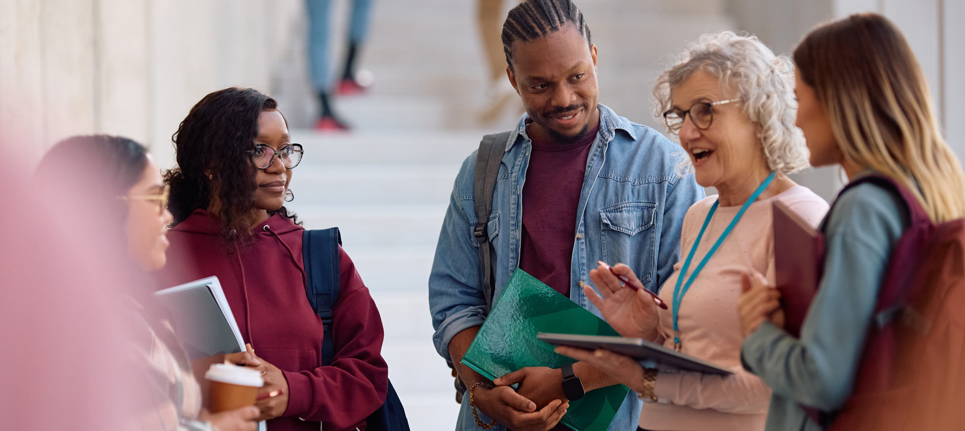 Multiracial Group Of Students And Their Professor Communicating In A Hallway