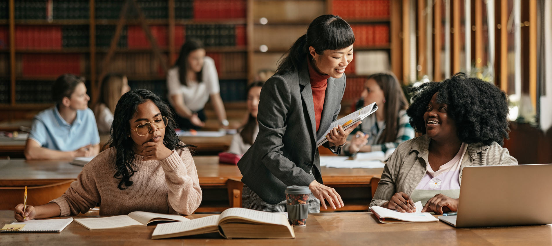 Femal Japanese Professor Standing Next To Student Teaching